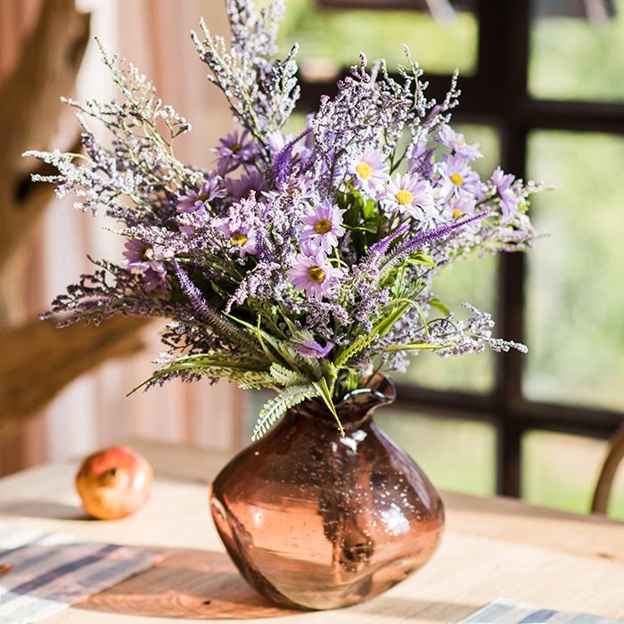 Bouquet of purple flowers in a brown vase on a table with a blurred background