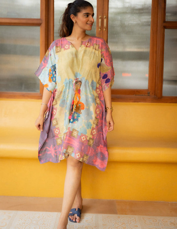 Woman wearing a colorful dress with floral patterns against a yellow wall.